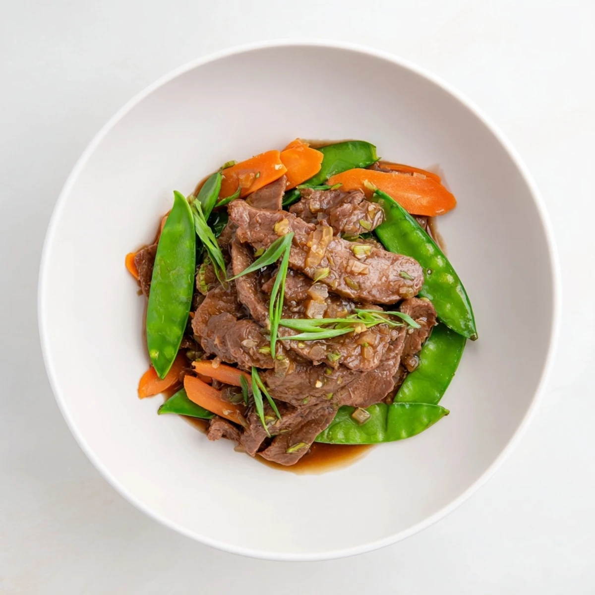 Sizzling Beef Stir Fry with Snow Peas and Carrots in a glossy, savory sauce, garnished with fresh ginger and scallions for a quick weeknight meal.  