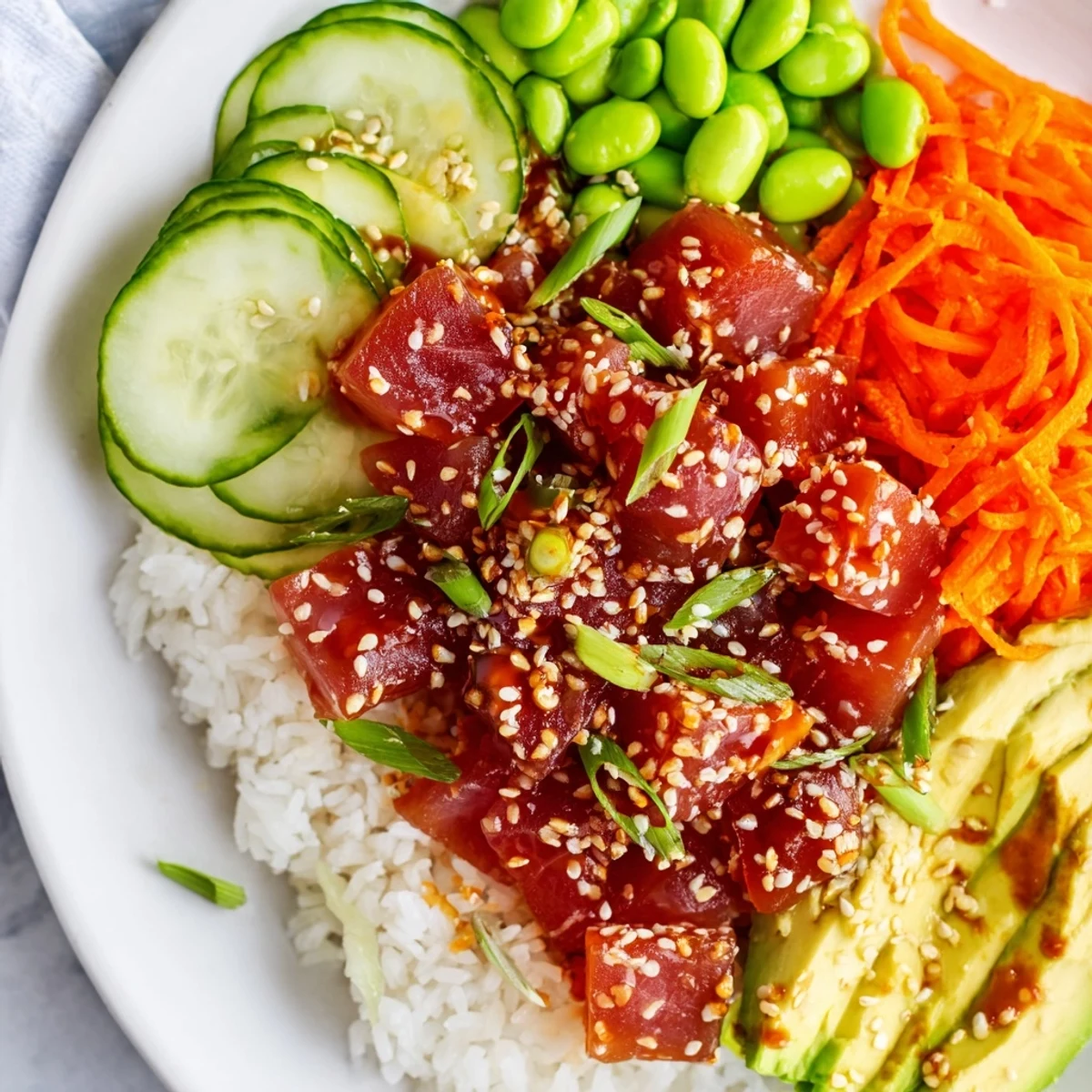 A close-up of a Spicy Tuna Poke Bowl with Avocado showing marinated tuna cubes, creamy avocado slices, and fresh veggies over fluffy rice.