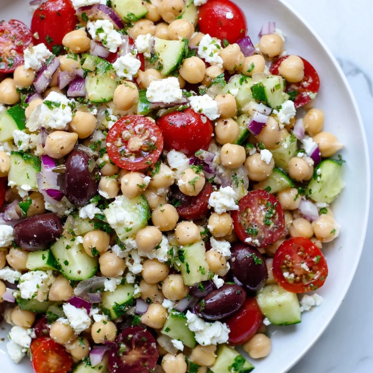 Colorful Mediterranean Chickpea Salad with crumbled feta, olives, and cucumbers tossed in lemon-olive oil dressing.