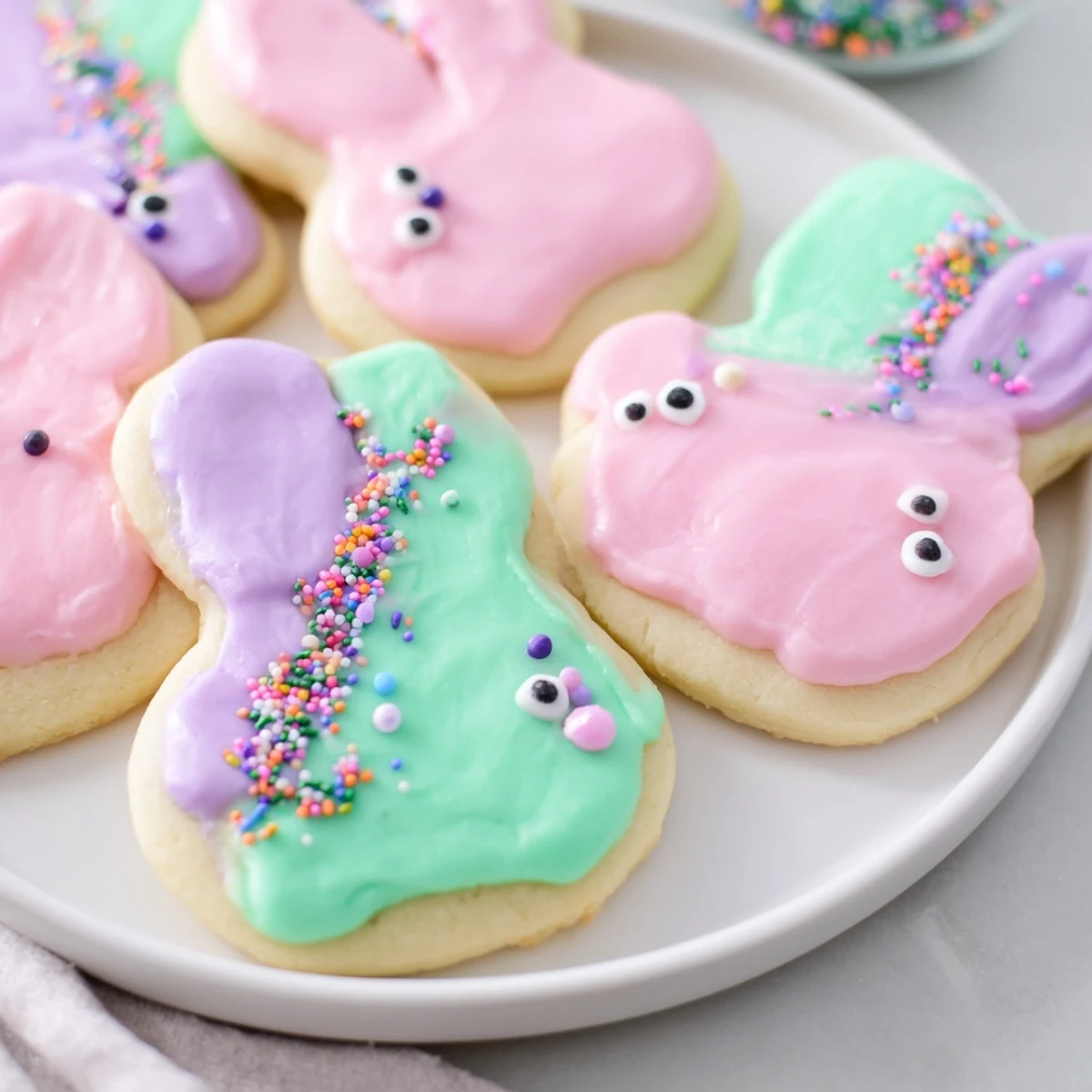 Golden-edged Easter Bunny Sugar Cookies decorated with pastel icing and candy eyes, ready to be served on a festive dessert platter.