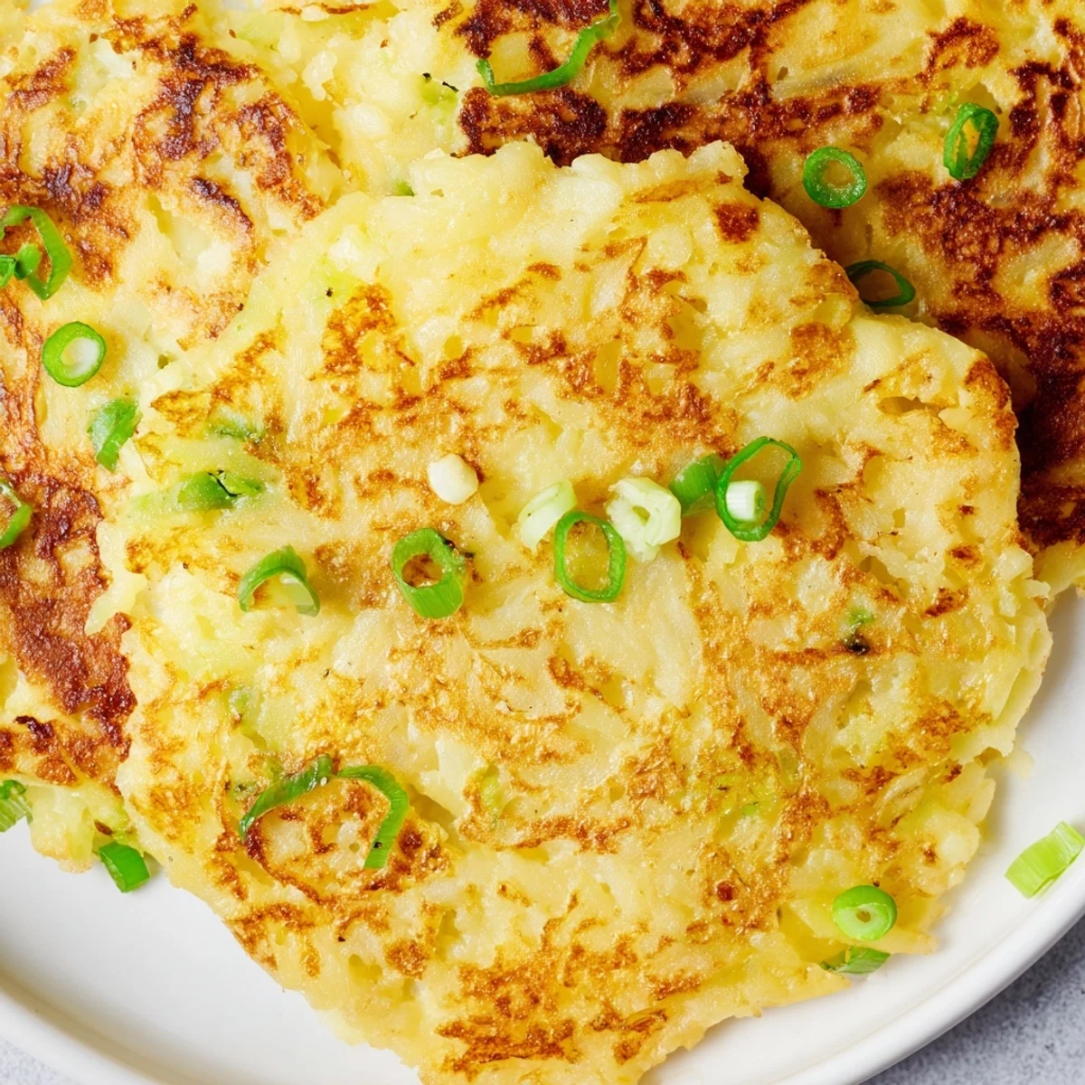 Golden-brown Irish Boxty Potato Pancakes garnished with scallions, perfect for breakfast or as a hearty side.