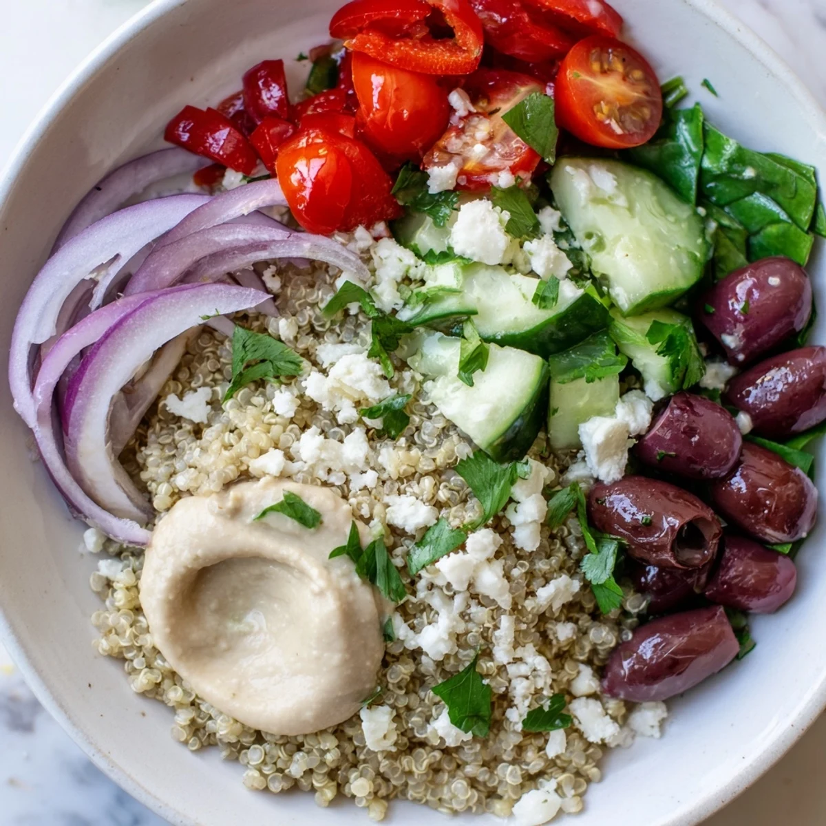 A wholesome Mediterranean Quinoa Bowl with fluffed quinoa, crisp vegetables, and a dollop of hummus, ready for a healthy lunch.