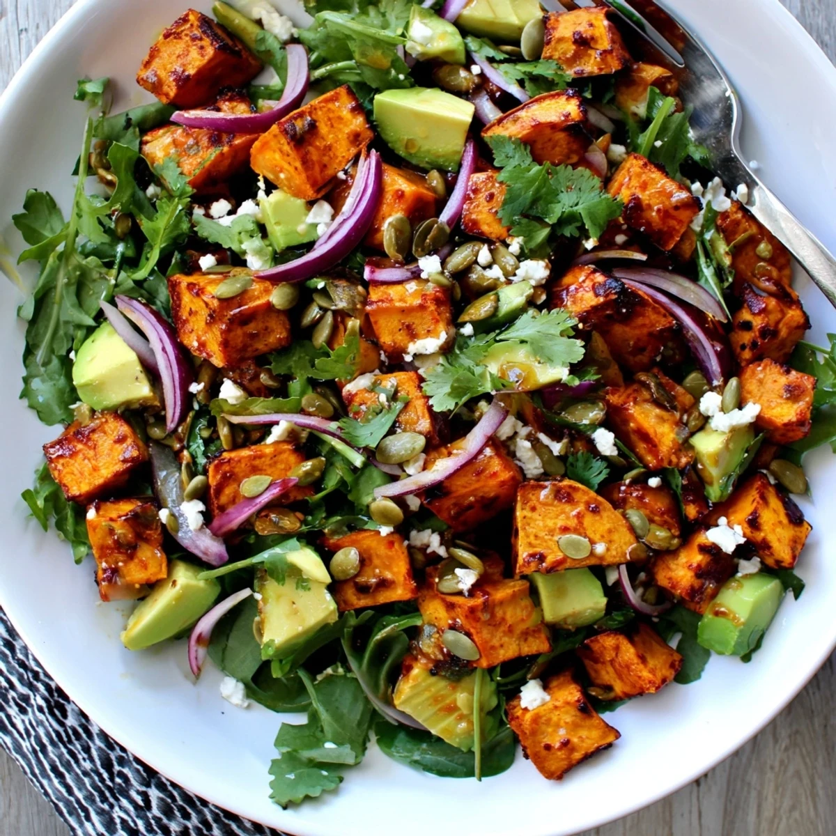 Roasted Sweet Potato Salad with Lime is plated in a shallow bowl with cilantro and pumpkin seeds, ready for a light vegetarian lunch.
