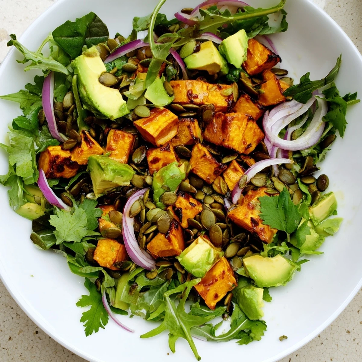 Roasted Sweet Potato Salad with Lime Dressing features caramelized cubes, creamy avocado, and zesty dressing on fresh greens.