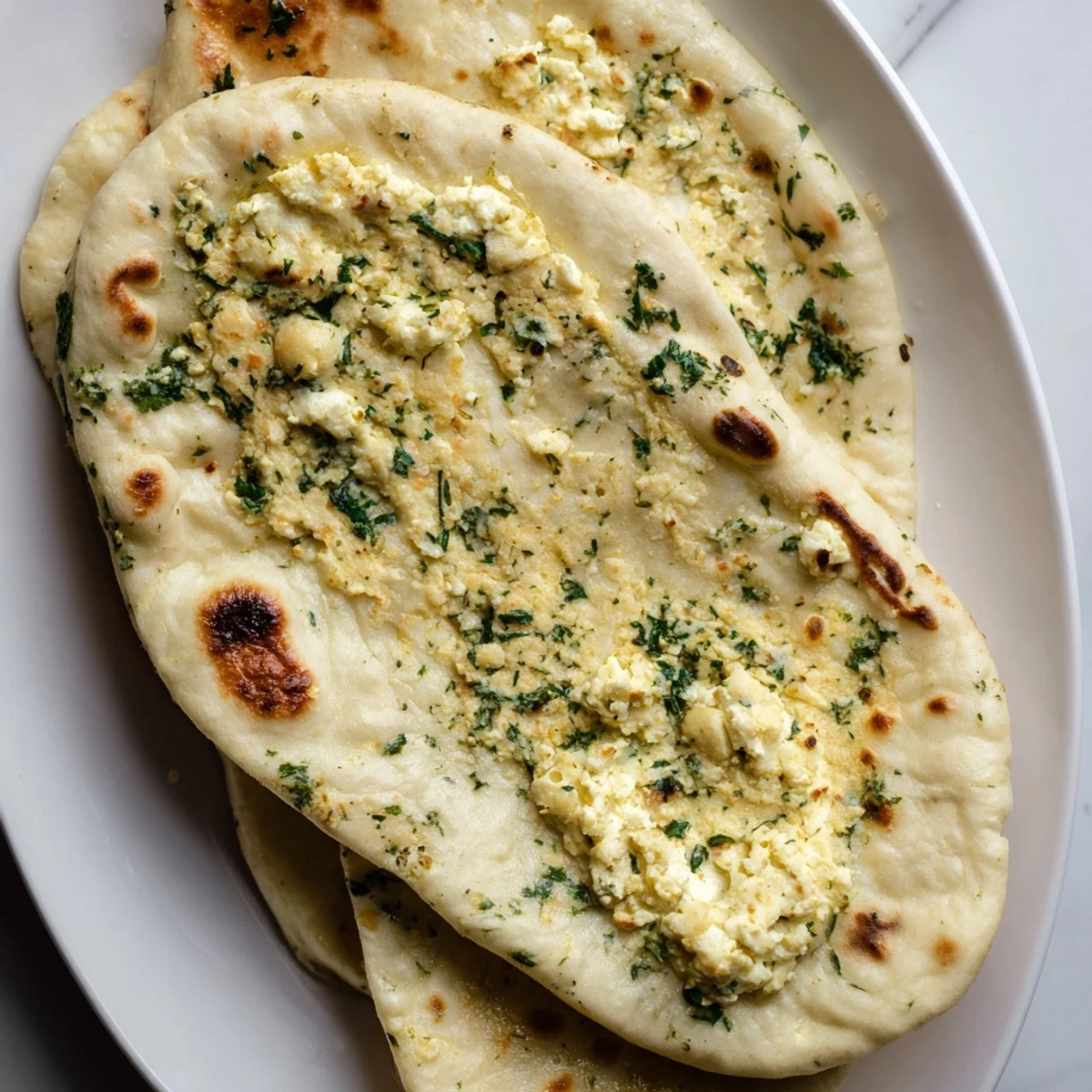 Soft, pillowy Cottage Cheese Garlic Naan fresh from the skillet shows golden spots and steam rising gently.