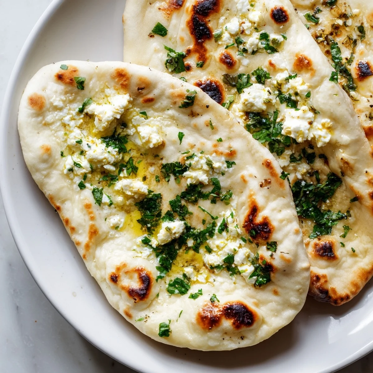 Stack of homemade Cottage Cheese Garlic Naan ready to serve with raita and dal for a comforting dinner.