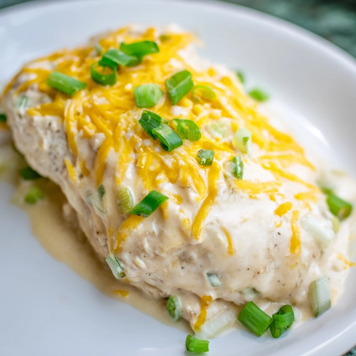 Golden baked Sour Cream and Onion Chicken sits in a dish with bubbly cheese topping, ready to be served with steamed veggies or mashed potatoes.