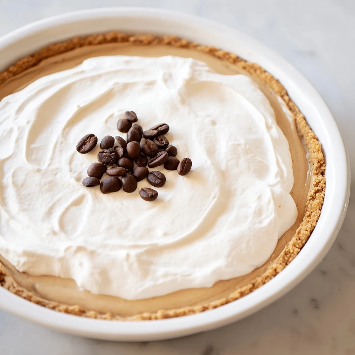 A slice of Keto Cold Brew Coffee Pie showing creamy filling on a golden almond crust with coffee bean garnish.