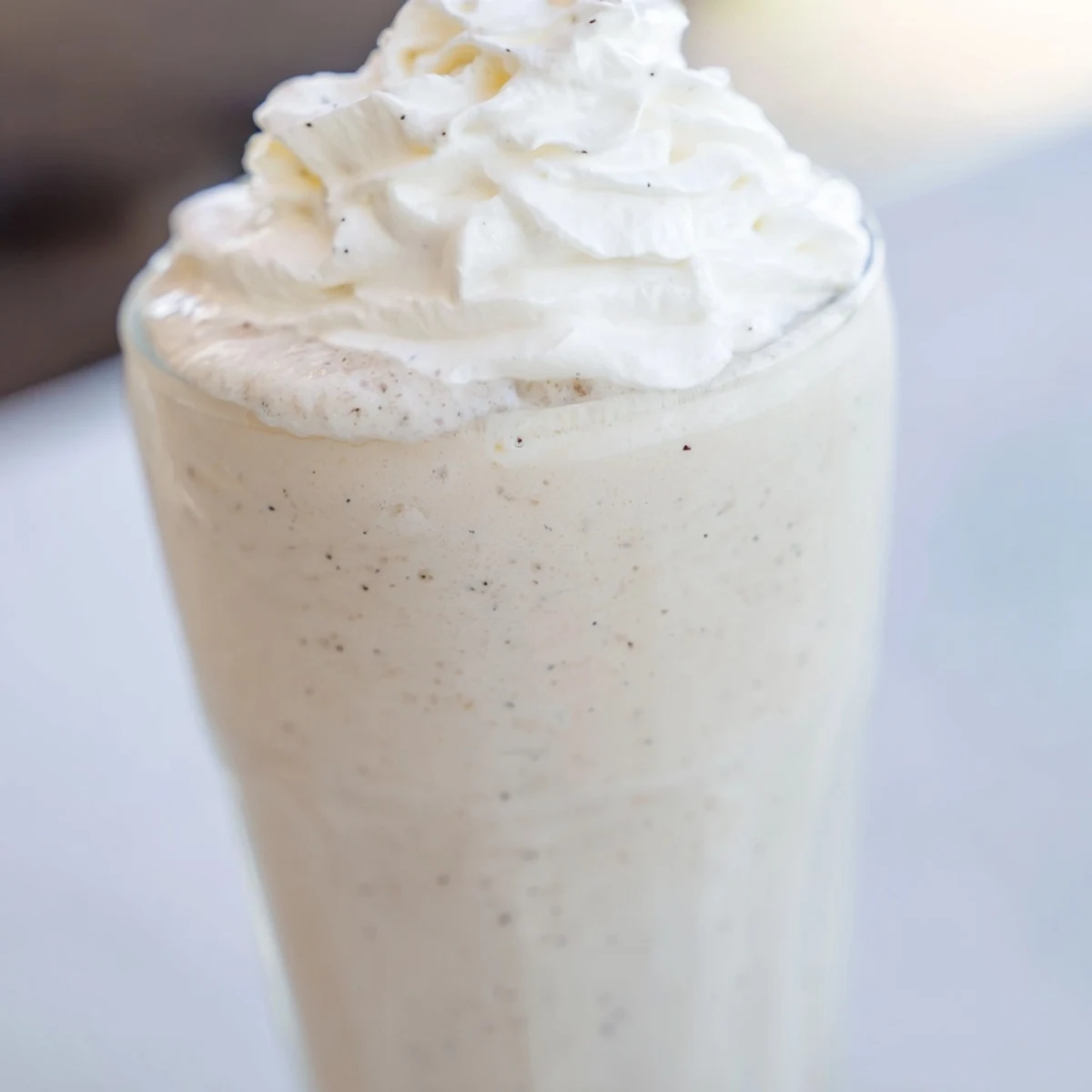 Frothy Starbucks Vanilla Bean Frappuccino topped with whipped cream in a tall glass.