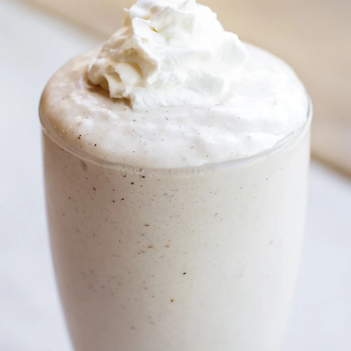 Two creamy Starbucks Vanilla Bean Frappuccinos with striped straws on a sunny brunch table.