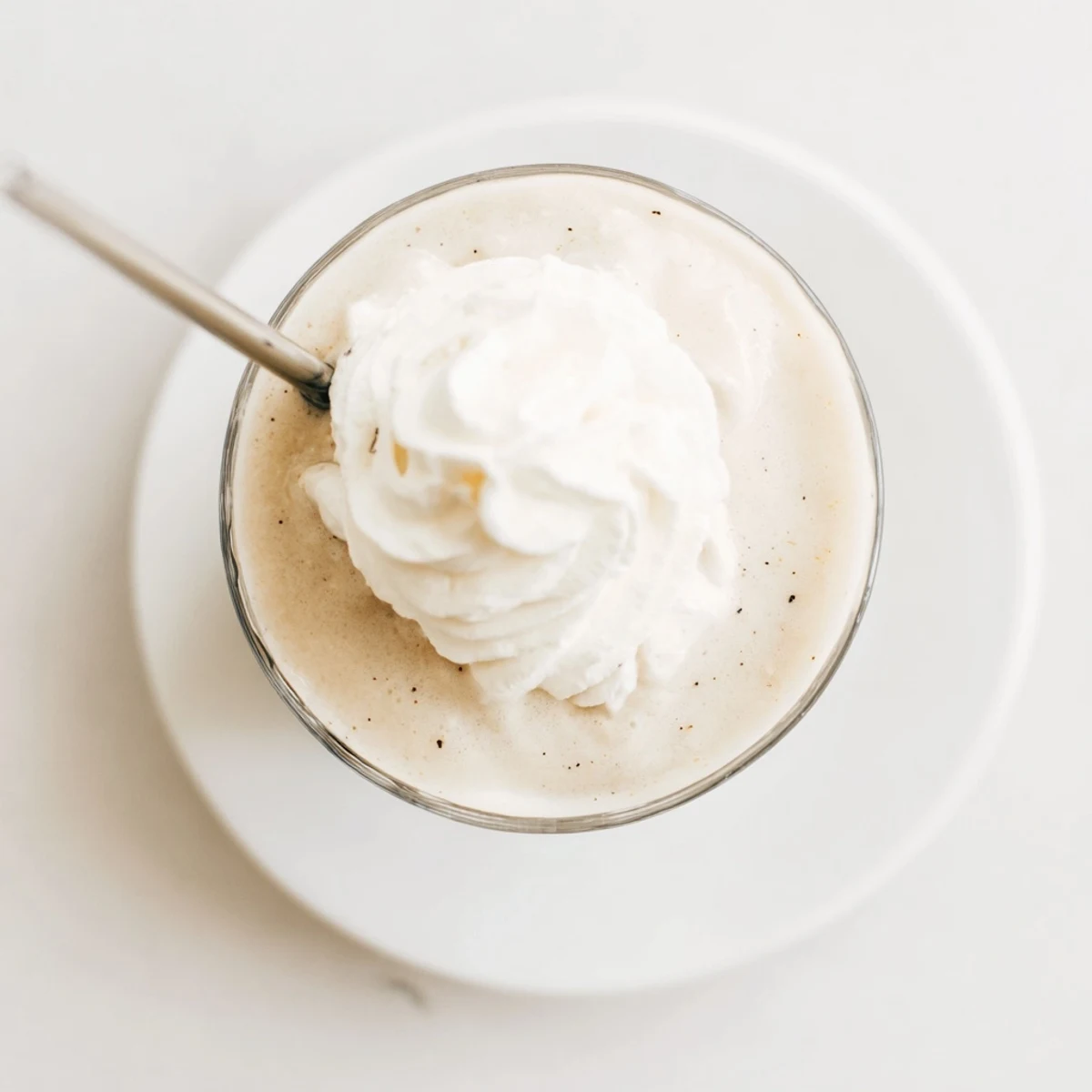 Creamy Vanilla Bean Frappuccino blended with ice cream and milk in a tall glass topped with whipped cream.