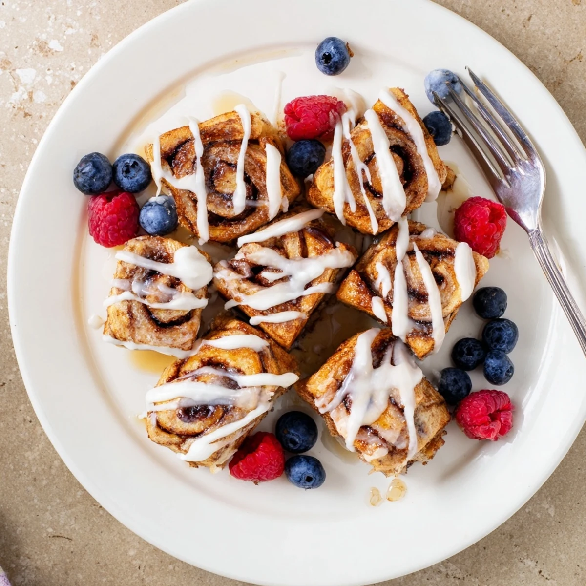 A stack of warm Cinnamon Roll French Toast Bites coated in maple syrup and powdered sugar for a sweet brunch treat.