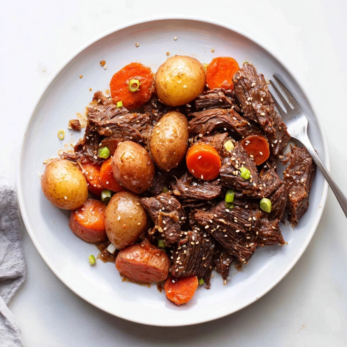 Fork-tender Slow Cooker Korean Beef Pot Roast with carrots and potatoes, drizzled with savory soy garlic gravy.