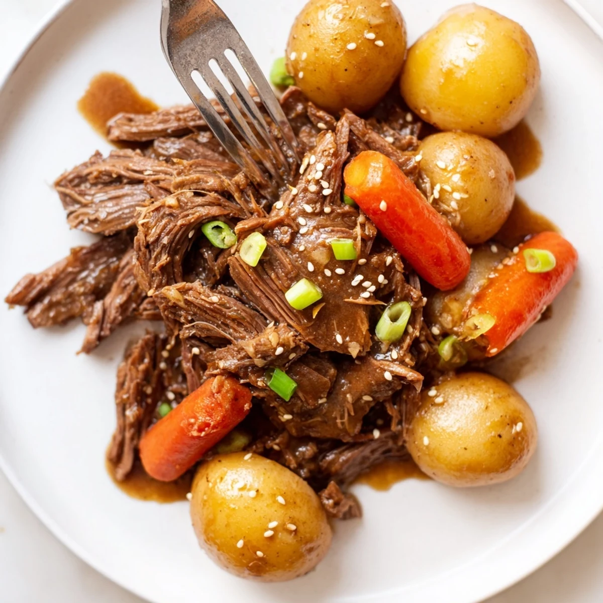 Hearty Slow Cooker Korean Beef Pot Roast served garnished with scallions and sesame seeds alongside steamed rice and kimchi.