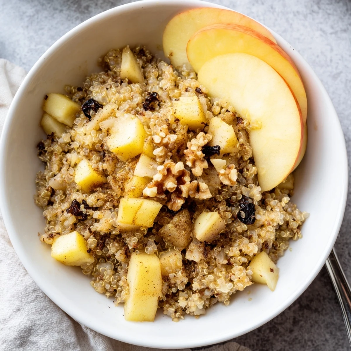 Fluffy quinoa apple breakfast bowl with warm cinnamon spices and crunchy walnuts topped with honey.