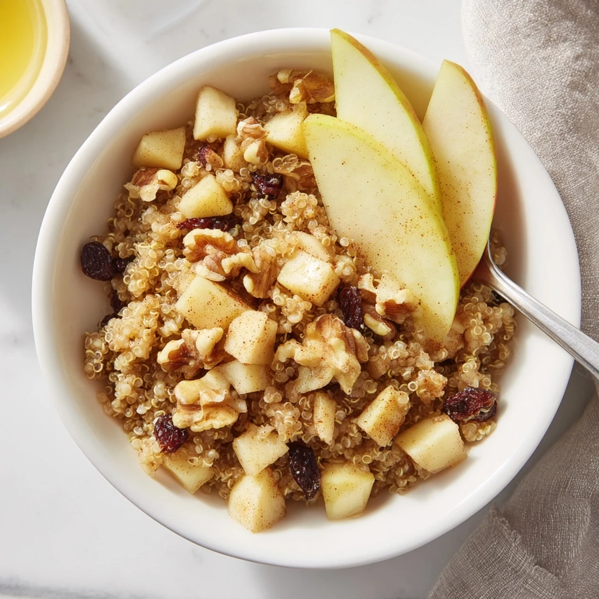 Warm healthy quinoa apple breakfast served with milk, raisins, and extra apple slices for a cozy morning.