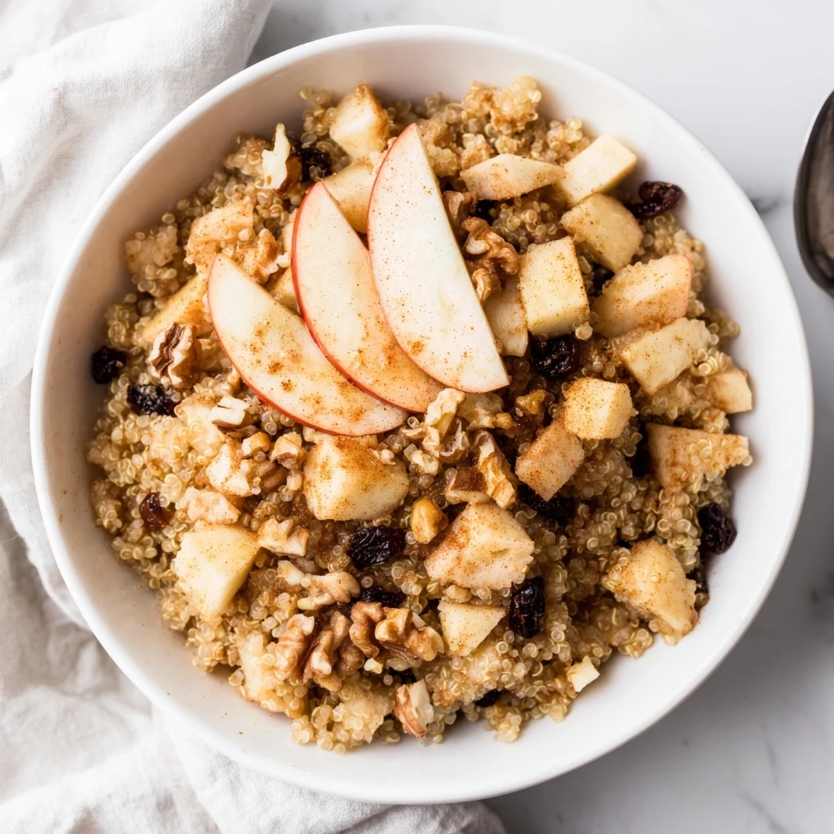 Creamy healthy quinoa apple breakfast cooked with diced apples, nutmeg, and a drizzle of maple syrup.