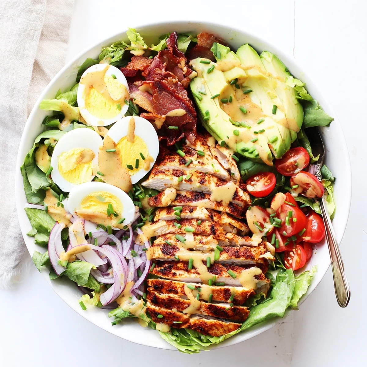 A vibrant serving of Paleo Grilled Chicken Cobb Salad With Honey Dijon Dressing highlights crisp romaine, red onion, and chives, perfect for a grain-free meal.