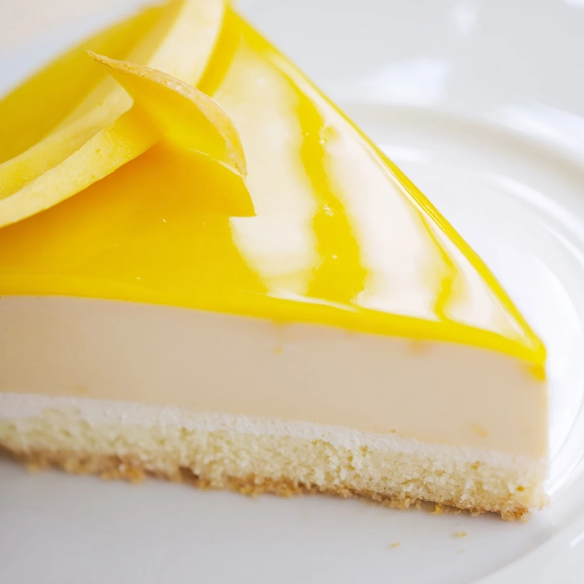Elegant mango mousse cake slice revealing creamy layers decorated with fresh mango and mint