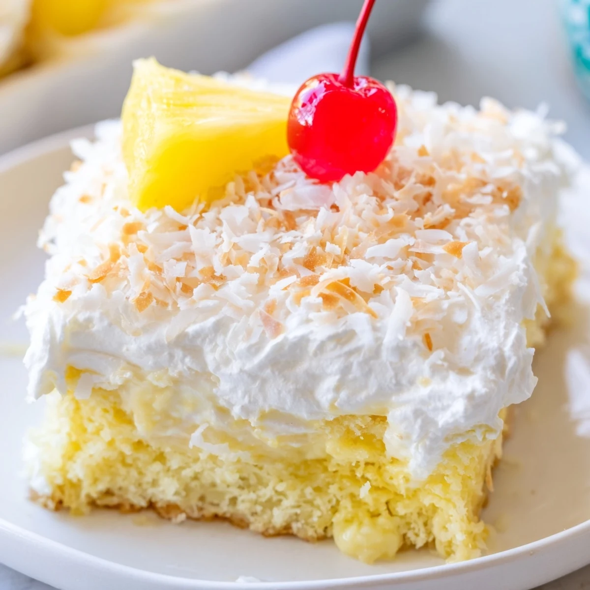 Slice of tropical Hawaiian poke cake drizzled with sweet coconut milk and garnished with fresh pineapple