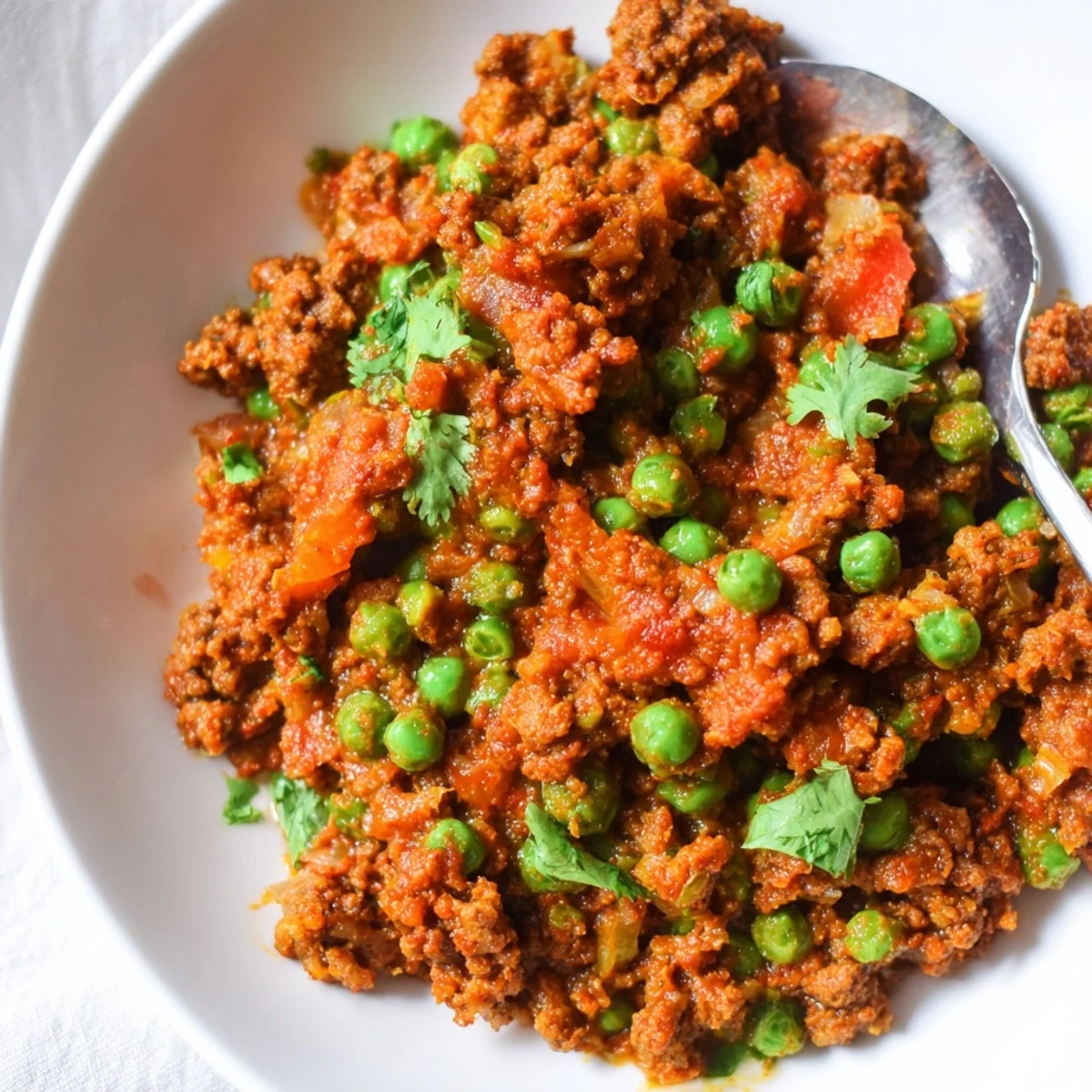 Golden ground beef Keema Curry simmered with aromatic spices, peas, and fresh cilantro garnish