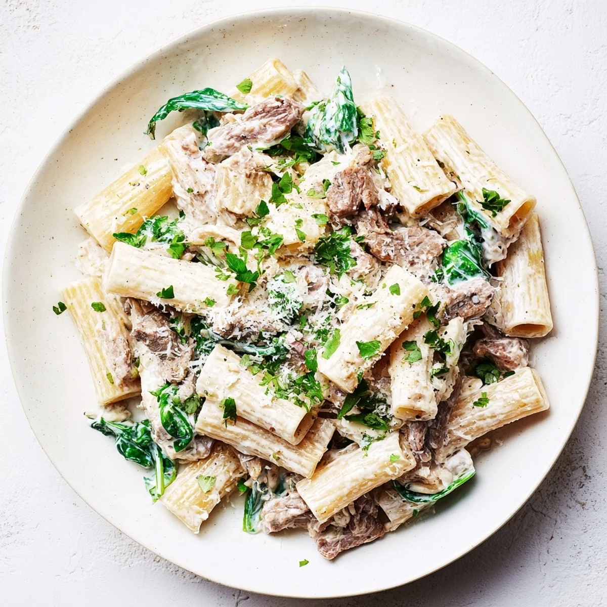 Bowl of high protein beef pasta featuring al dente noodles coated in a velvety yogurt cottage cheese sauce with savory beef strips