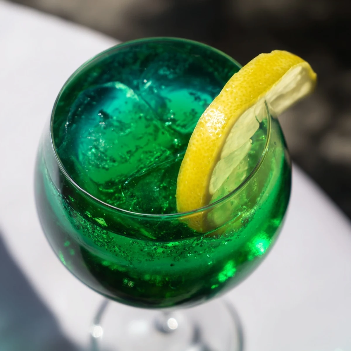 Vibrant Luck of the Irish cocktail with emerald green hue, garnished with fresh mint sprig in chilled glass.