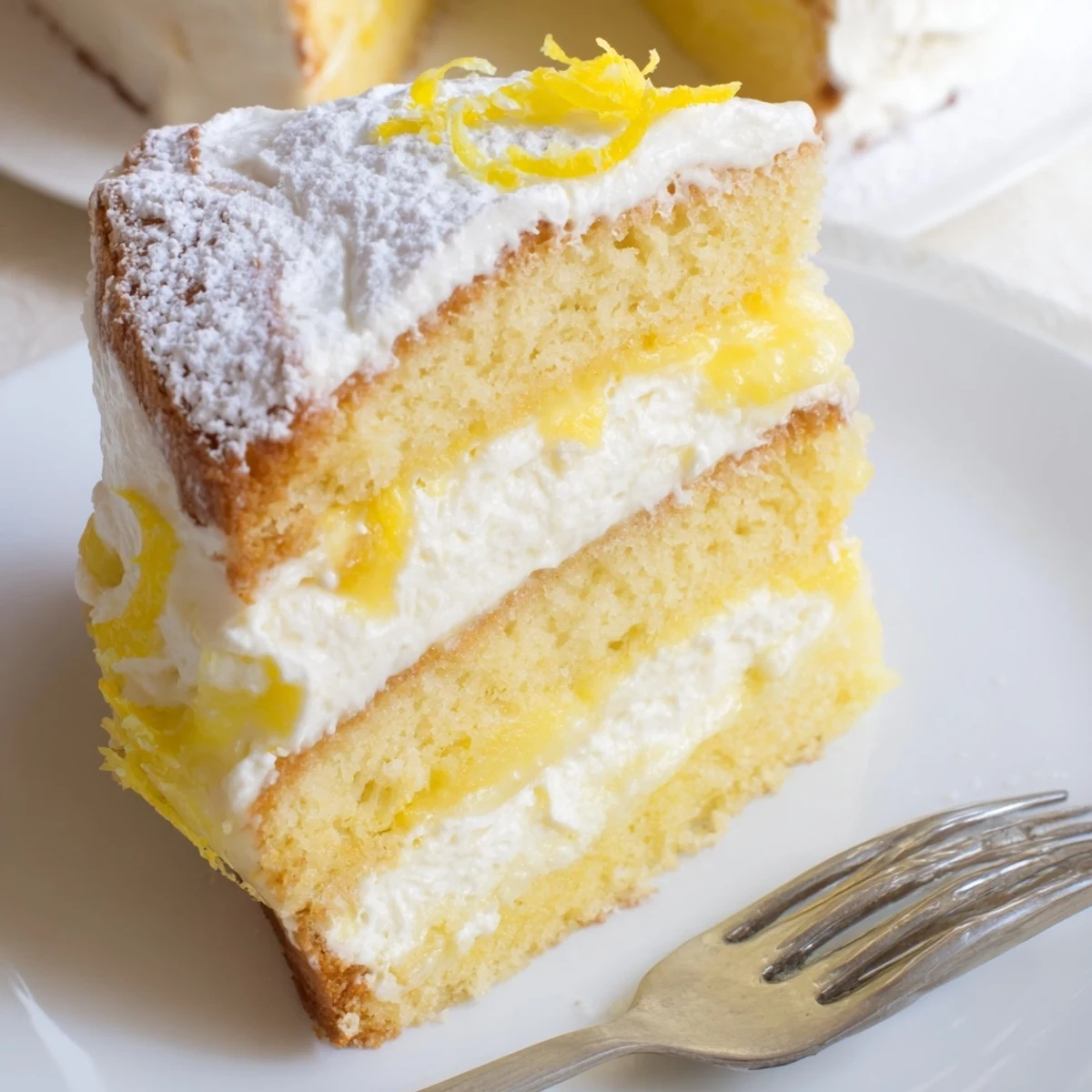 Golden Italian lemon cream cake with fluffy layers and smooth mascarpone filling dusted in powdered sugar