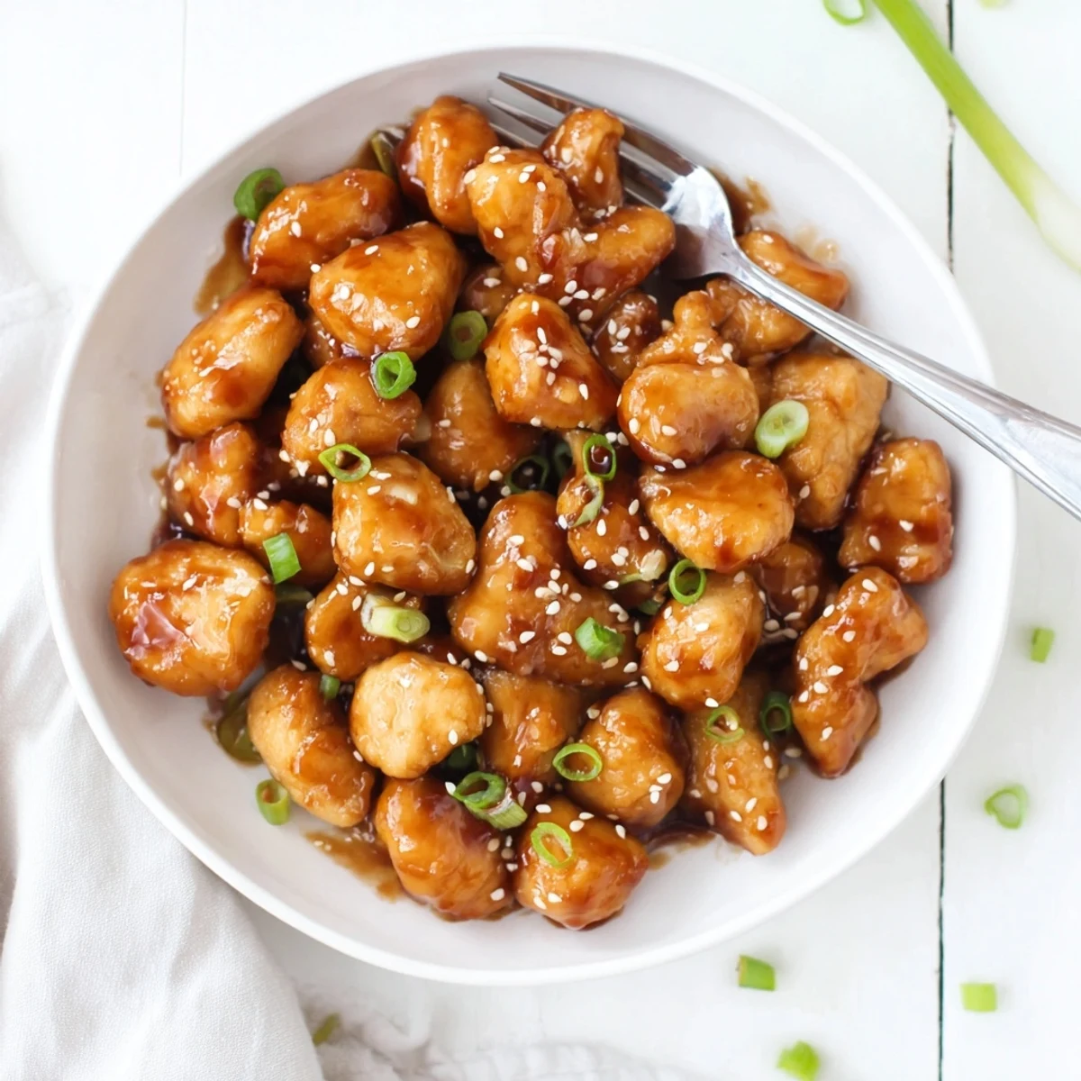 Golden brown honey garlic chicken pieces coated in sticky sweet glazed sauce with green onion garnish