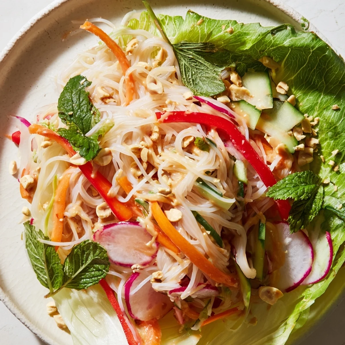 Fresh spring roll salad with peanut dressing arranged in butter lettuce cups with colorful shredded vegetables