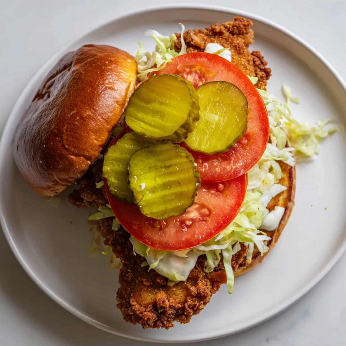 Homemade spicy chicken sandwich featuring juicy breaded meat dripping with white sauce on soft toasted bread