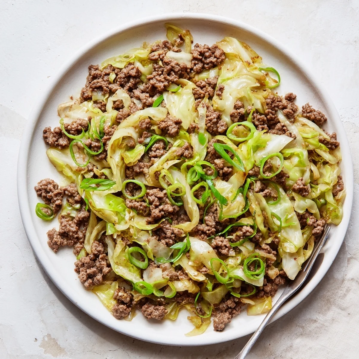 Golden brown low carb Mongolian ground beef and cabbage stir-fry in a white bowl
