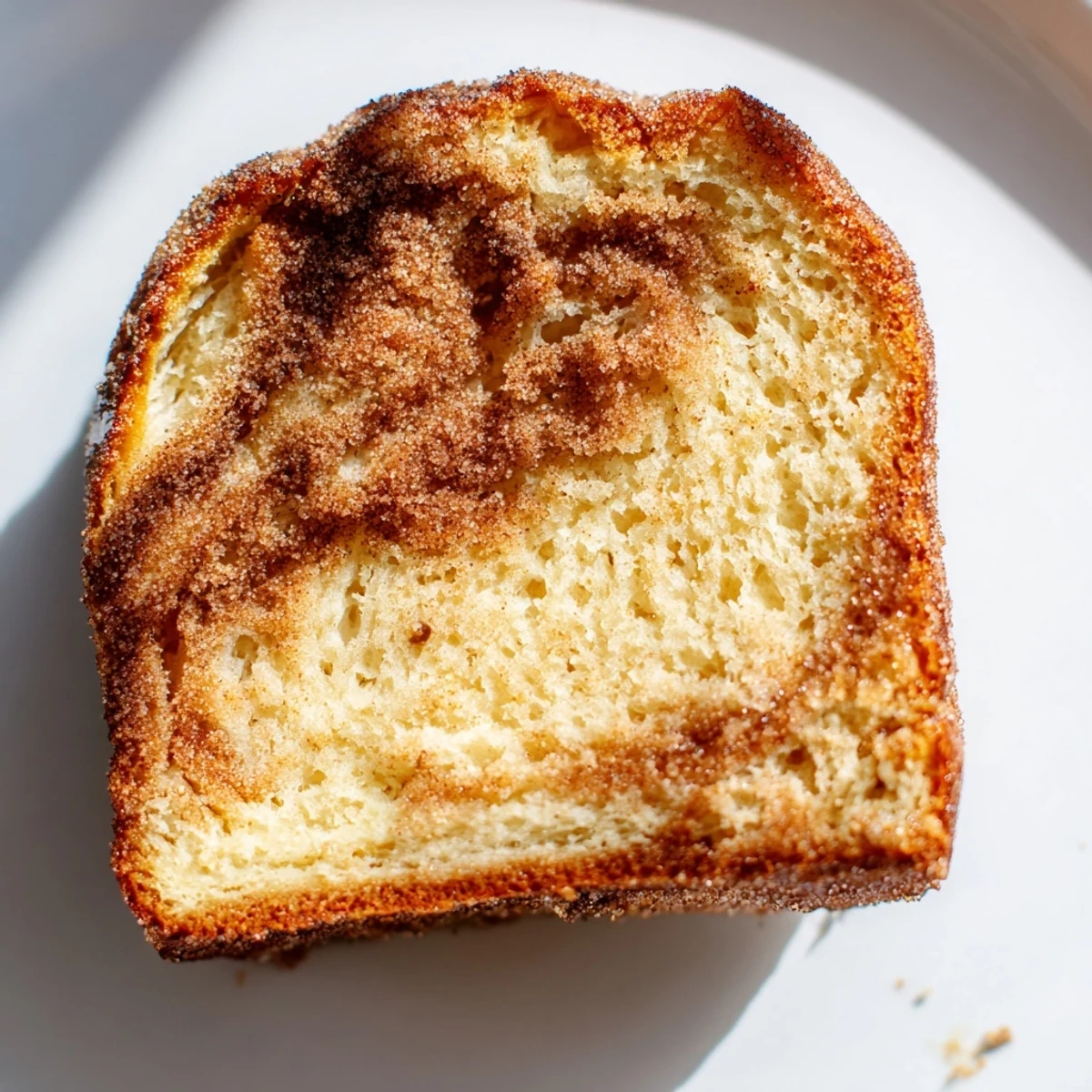 Sliced cinnamon sugar donut bread served on a white plate with coffee or chai