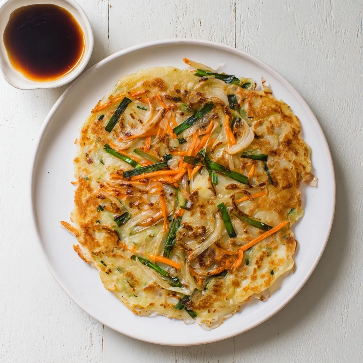 Sliced wedges of hot crispy Korean pancakes served with soy dipping sauce on a wooden board