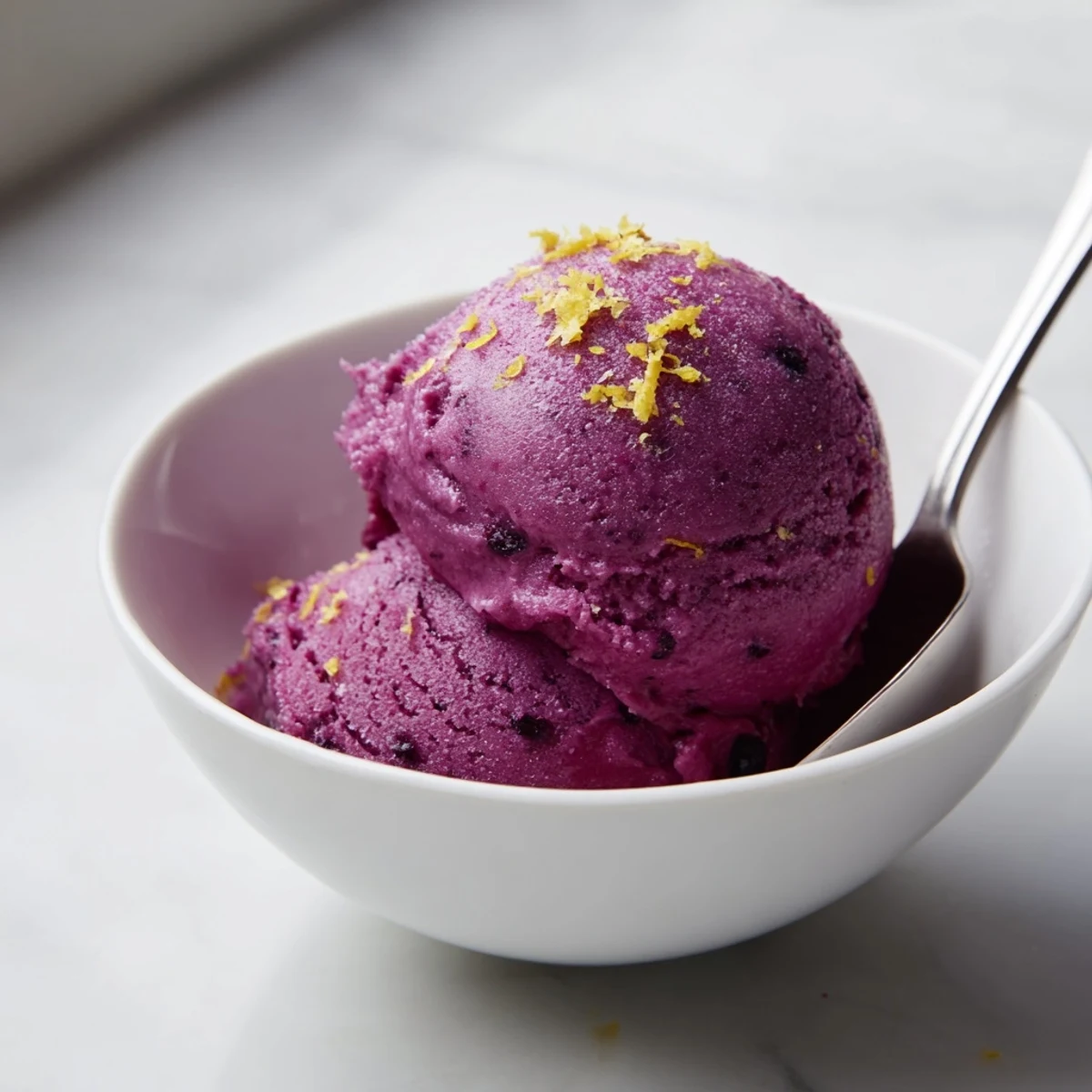 Vibrant no churn blueberry lemon sorbet scooped into chilled bowls with fresh blueberry garnish