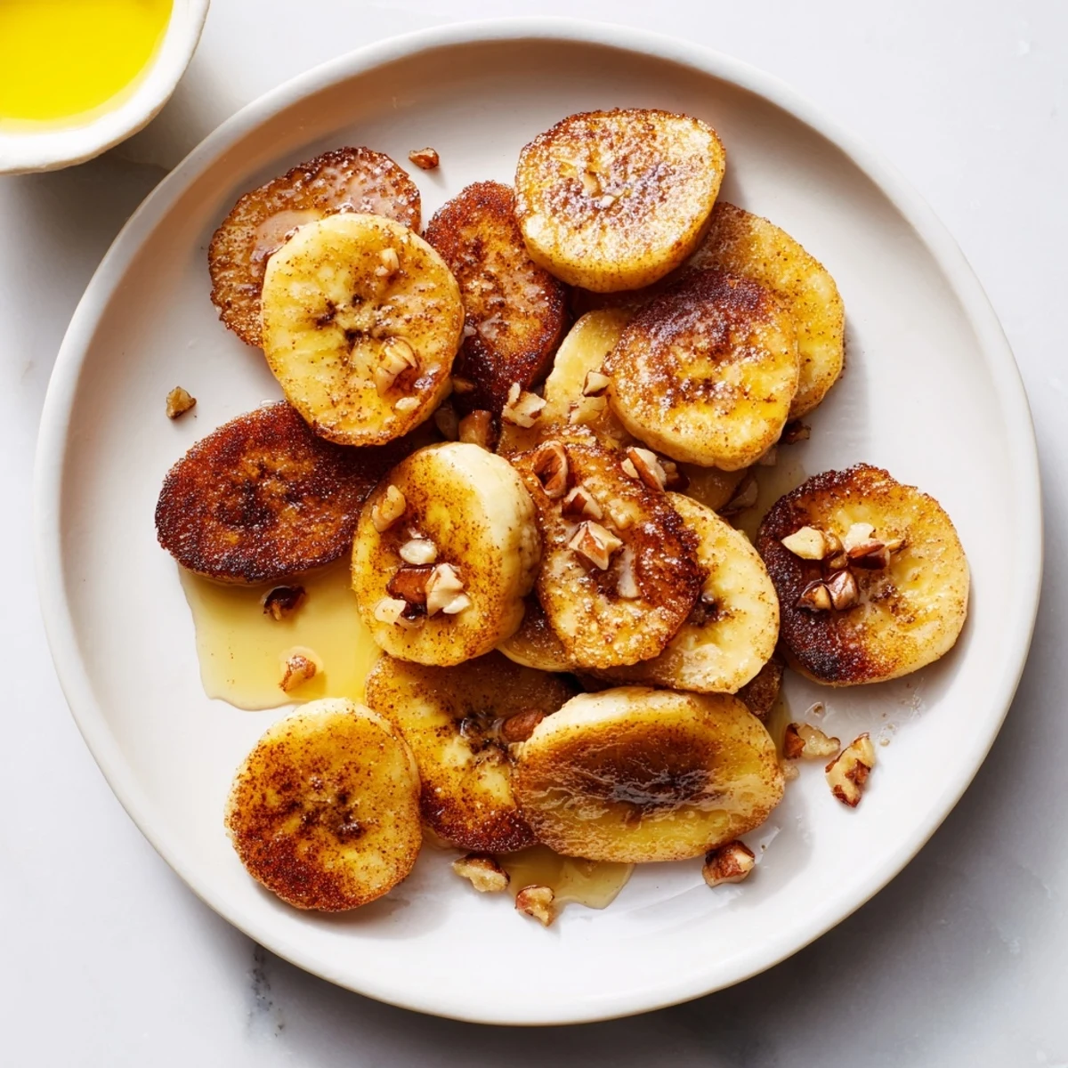 Crispy cinnamon sugar coated banana slices arranged on a white plate after pan frying