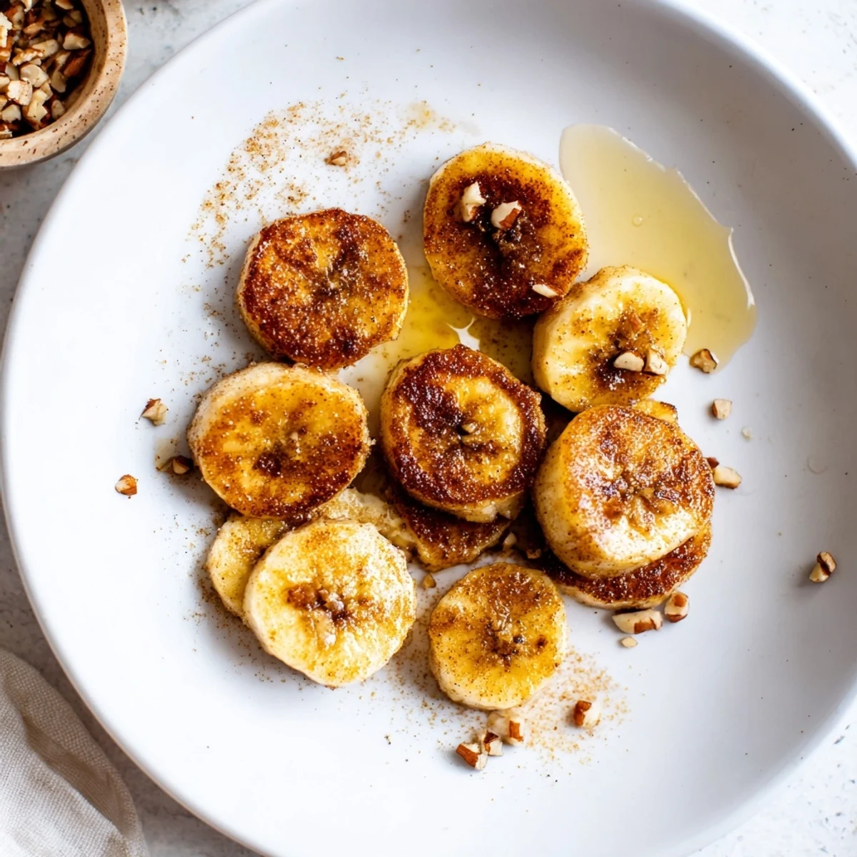 Warm caramelized pan fried cinnamon bananas served in a cast iron skillet with melted butter pooling around golden edges