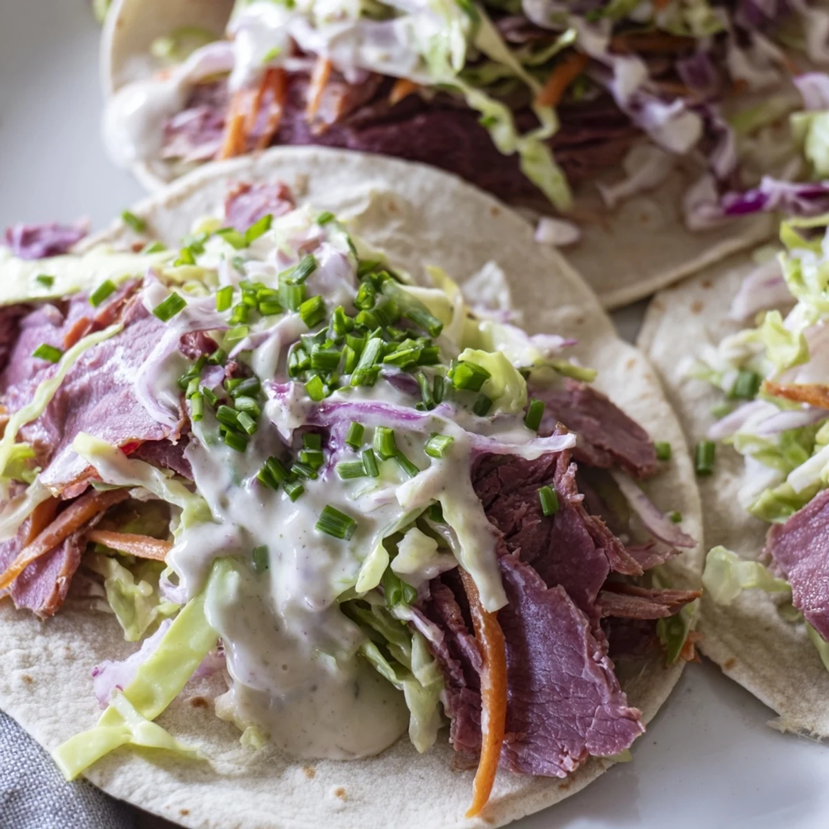 Handheld Irish Mexican tacos featuring shredded beef, zesty slaw, and tangy sour cream