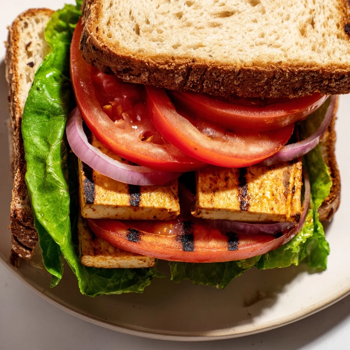 Smoky Tofu TLT Sandwich stacked with ripe tomatoes and crisp lettuce on toasted sourdough