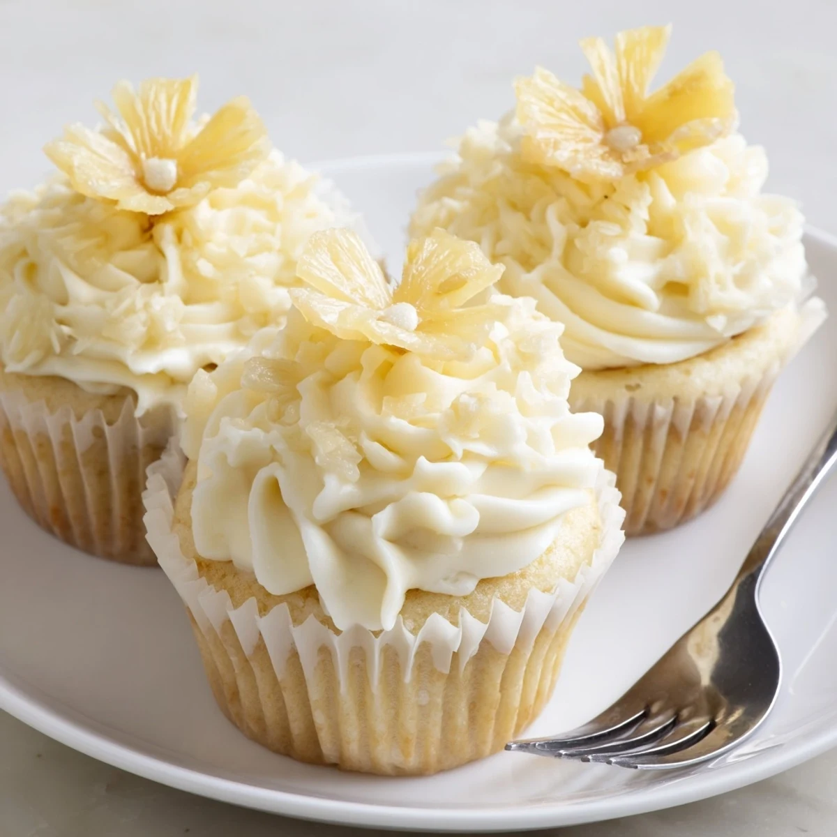 Plate of Dole Whip Cupcakes Recipe garnished with dried pineapple and cherry