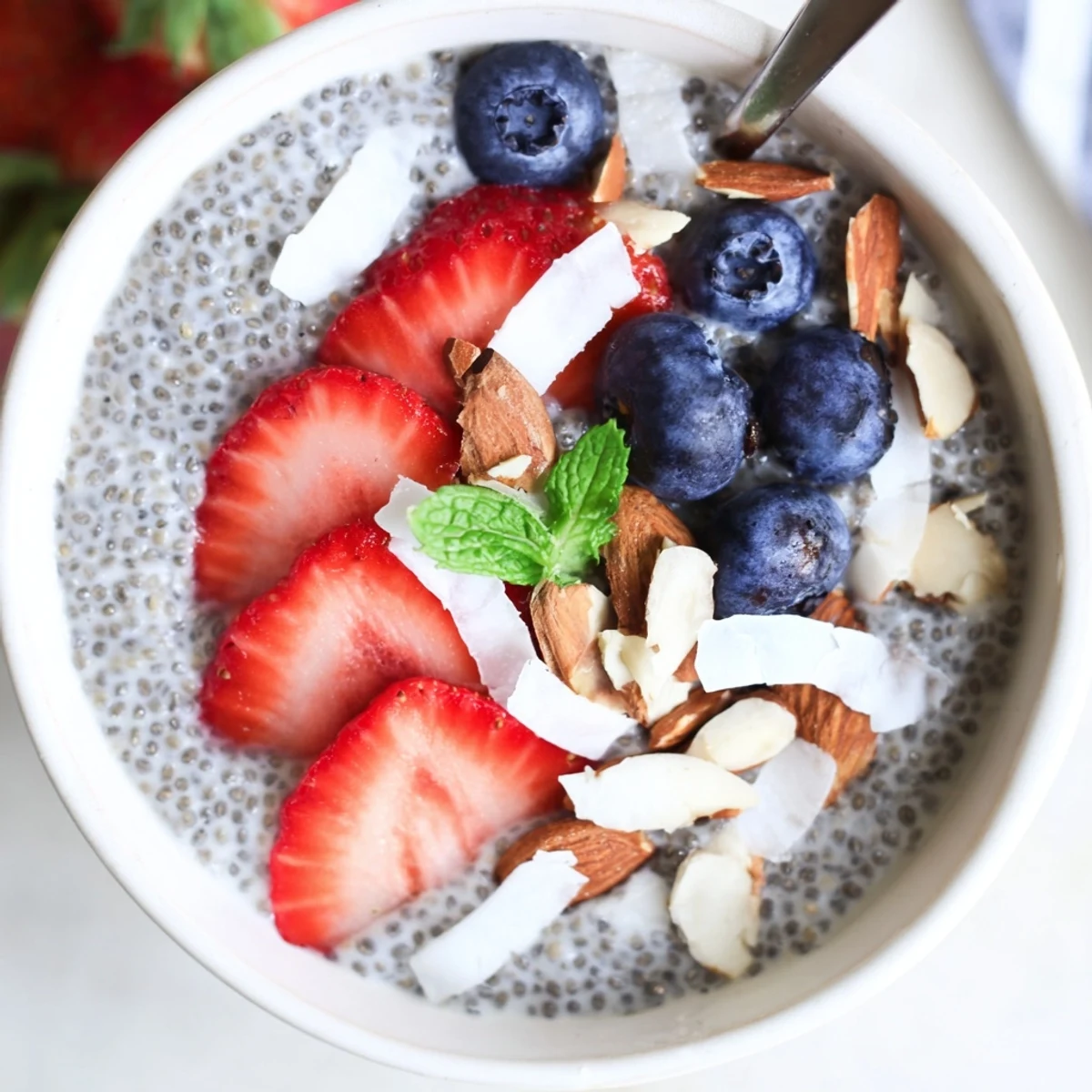 Creamy Chia Seed Pudding topped with fresh berries, mint, and crunchy nuts