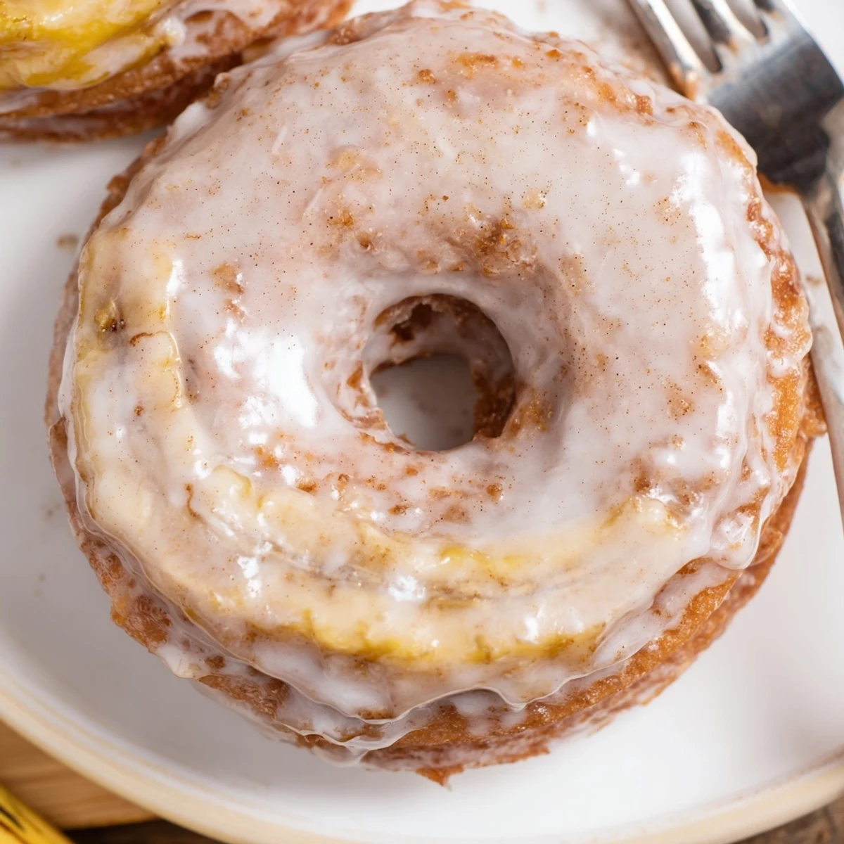 Golden Banana Donuts dusted with powdered sugar, served beside coffee mug.