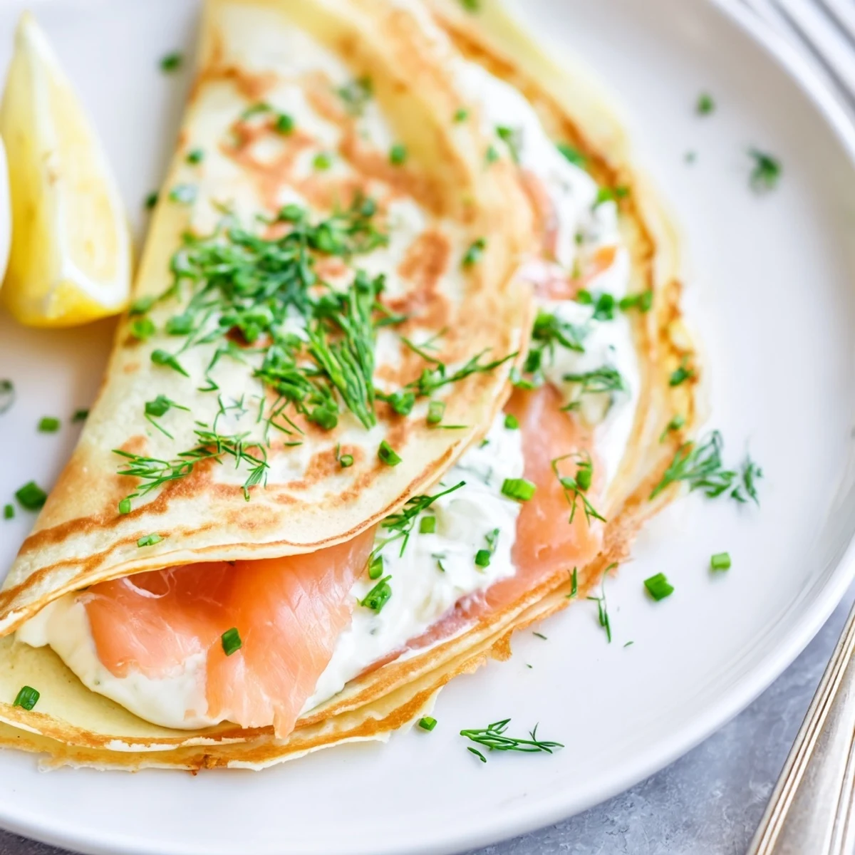 Bright brunch platter featuring Smoked Salmon Crepes Recipe garnished with fresh dill and wedges