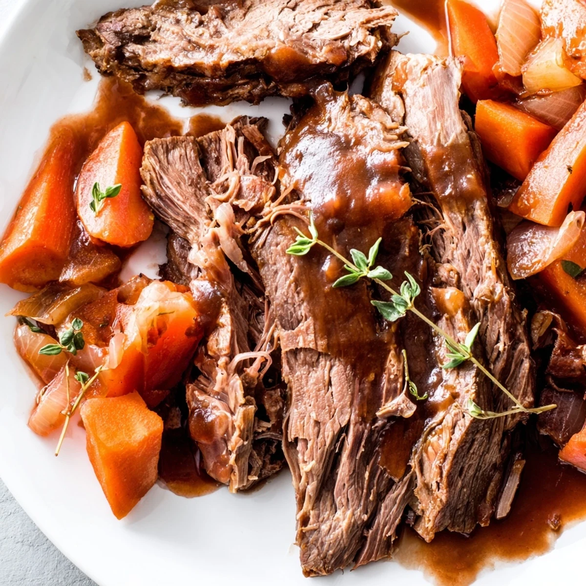 Golden brown herb braised beef chuck roast plated alongside carrots celery and baby potatoes