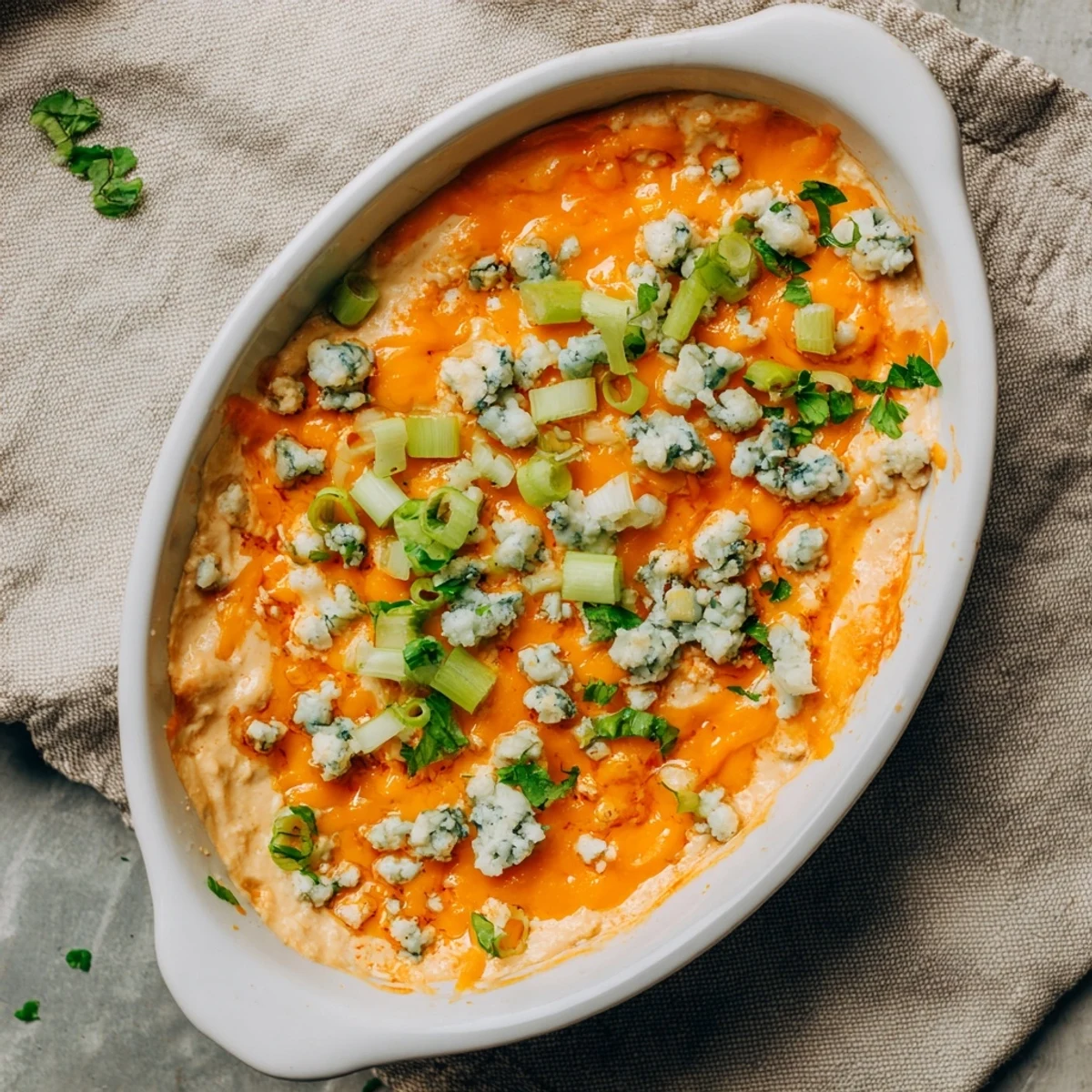Golden bubbling cheesy white bean buffalo dip topped with melted sharp cheddar and fresh green onions