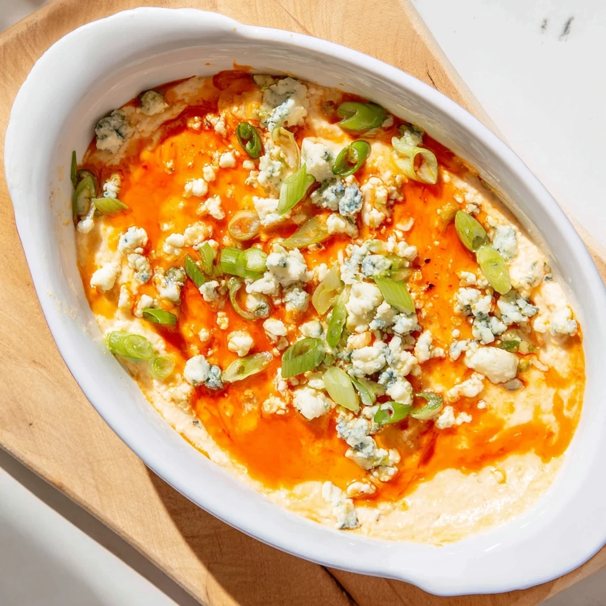 Steaming hot white bean buffalo dip with tortilla chips for dipping featuring spicy orange buffalo sauce swirls