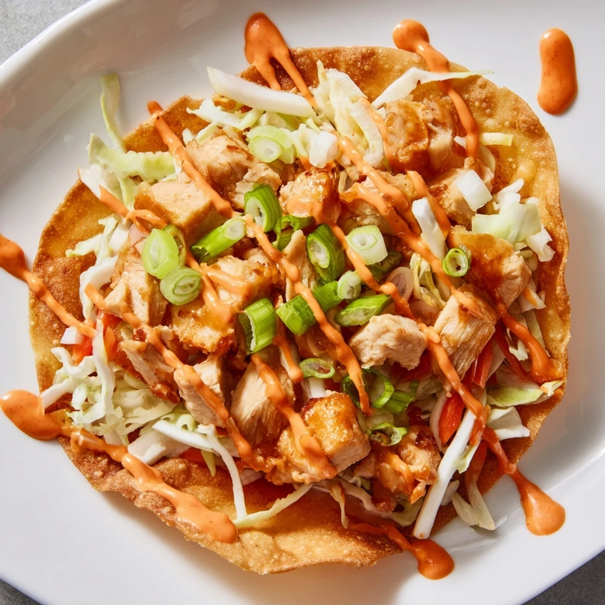 Crispy chicken wonton tacos topped with colorful slaw and spicy sriracha mayonnaise drizzle