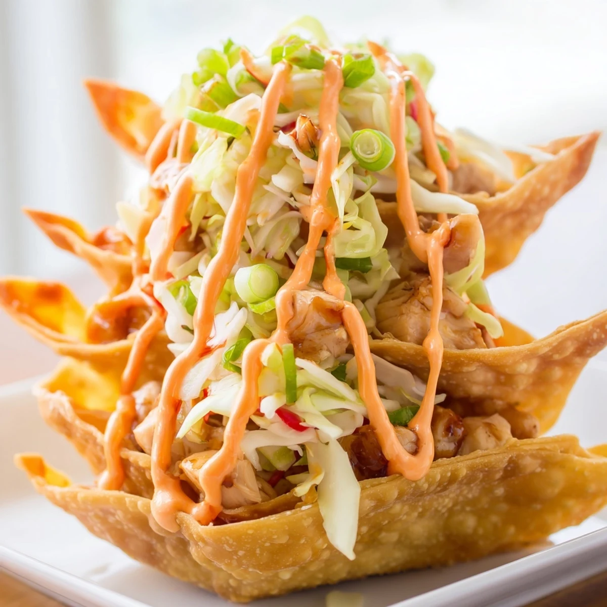 Asian fusion chicken wonton tacos arranged on serving platter with zesty lime crema topping