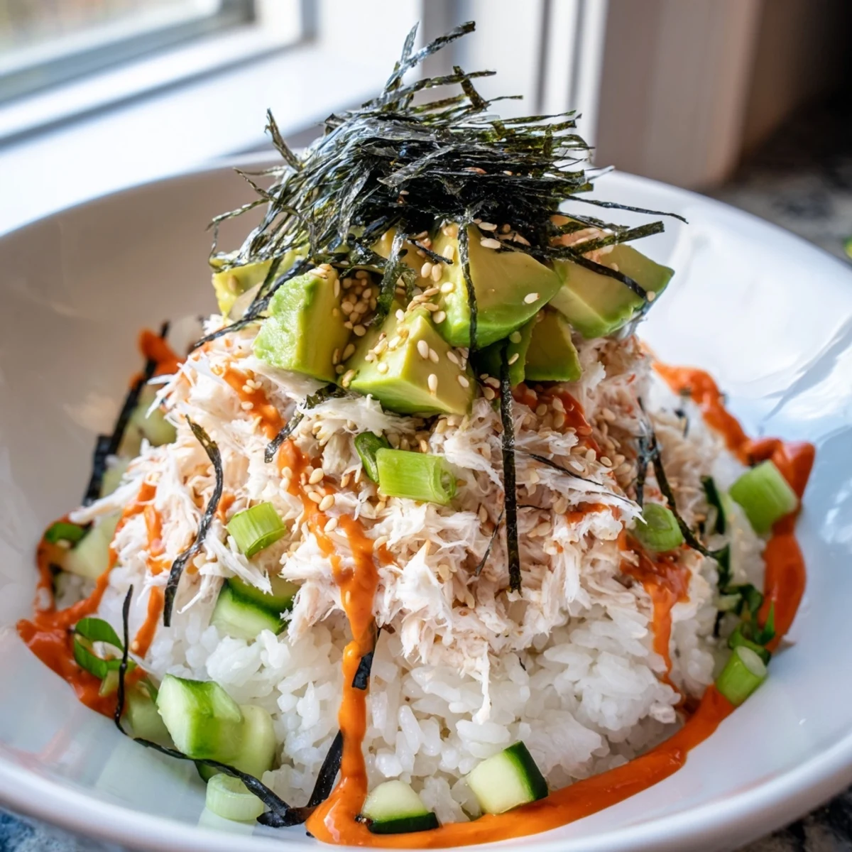 Homemade California roll sushi bowl piled high with diced avocado, julienne cucumber, nori strips, and toasted sesame seeds.