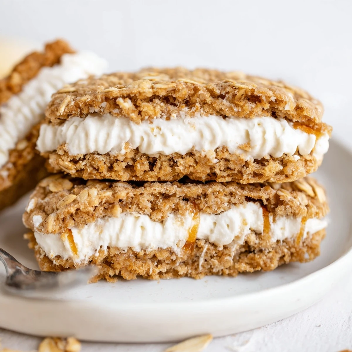 Stacked Gluten Free Oatmeal Creme Pies on plate, dusted with powdered sugar.